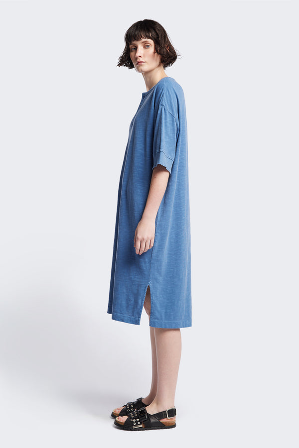 Side of the Treatise Henley Dress in Blue soft jersey, featuring a relaxed boxy fit, crew neckline, henley button detail, and falling just below the knee. Available in 5 sizes.