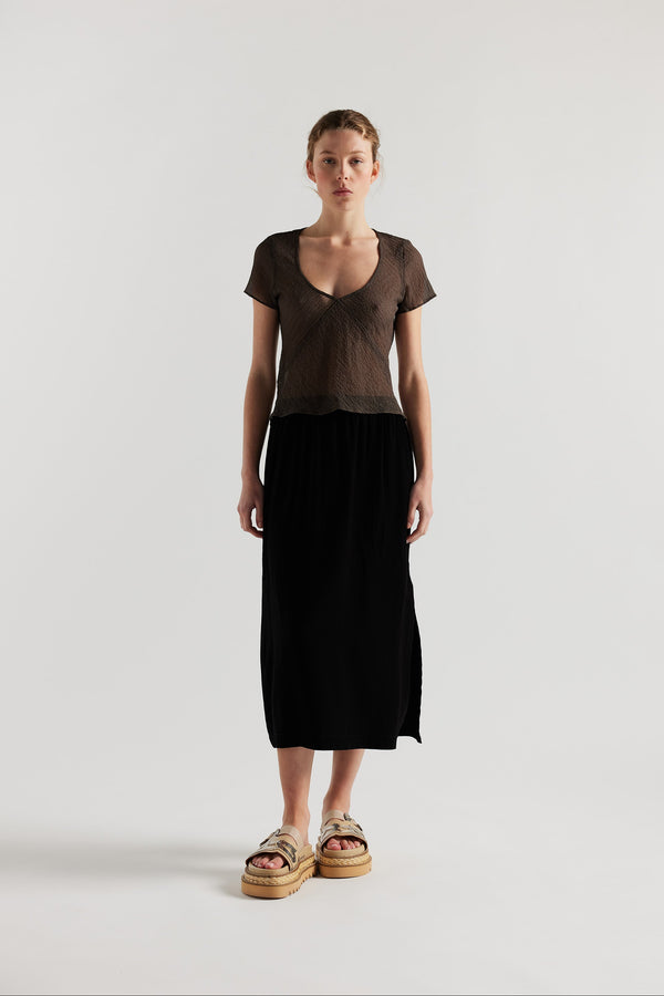 Front view on model of Mid-length slip skirt in black soft viscose-rayon. Ft. elasticated gathered waist with self-tie pull and side split visible.