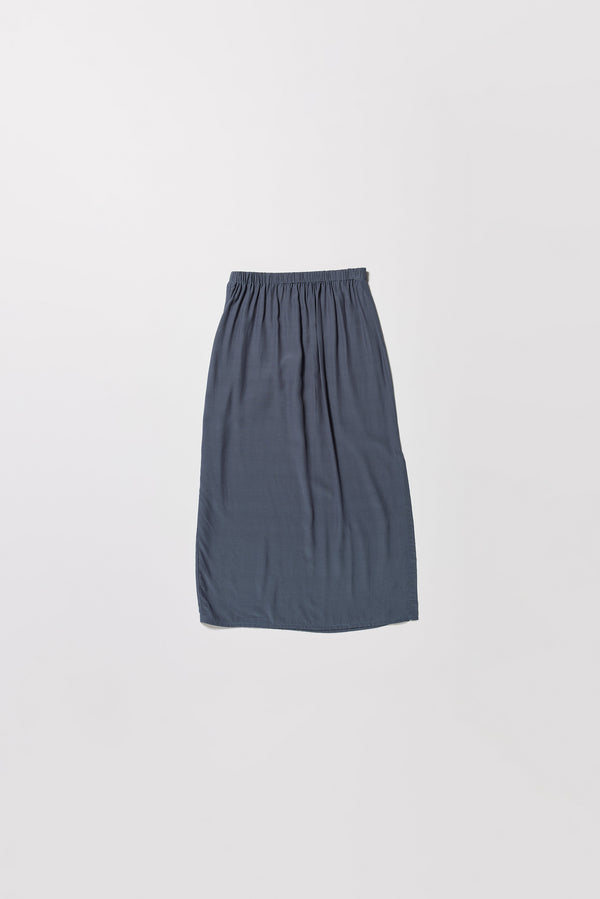 Flat back of Mid-length slip skirt in indigo soft viscose-rayon. Ft. elasticated gathered waist with self-tie pull and side split visible.