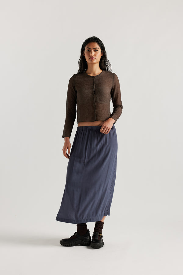 Front view on model of Mid-length slip skirt in Indigo soft viscose-rayon. Ft. elasticated gathered waist with self-tie pull and side split visible.