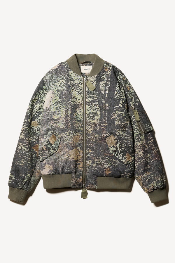 Flat Front of Unisex bomber jacket in Green Print woven jacquard with real tree camouflage, featuring dropped shoulders, ribbed trims, and full-length front zip.