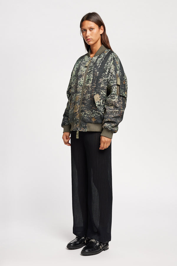 Women - Front of Unisex bomber jacket in Green Print woven jacquard with real tree camouflage, featuring dropped shoulders, ribbed trims, and full-length front zip.