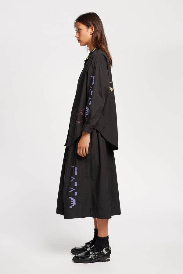 Side view of Model in the Black Universe Embroidered Skirt showcasing Arecibo-inspired motifs.