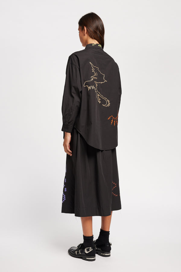 Back view of Model in the Black Universe Embroidered Skirt showcasing Arecibo-inspired motifs.