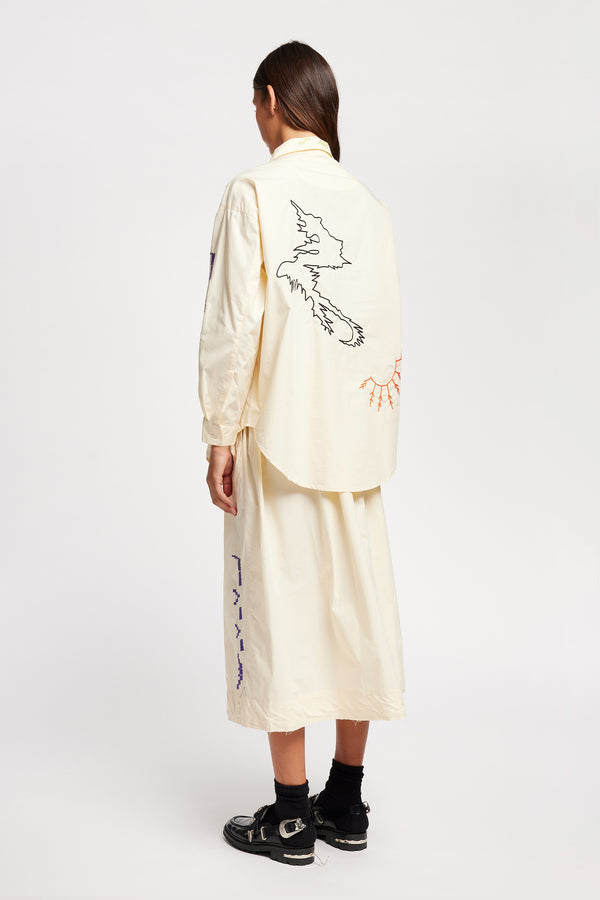 Back view of Model in the Ecru Universe Embroidered Skirt showcasing Arecibo-inspired motifs.