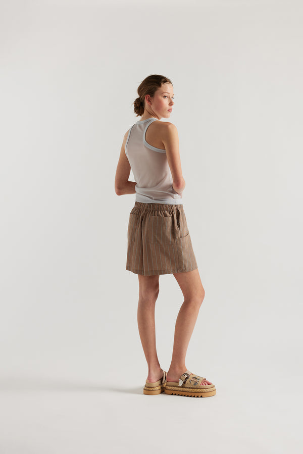 Back view of model in the the burnt orange, ecru and black stripe vesper short, a wide loose fit short with elasticated waistband. 