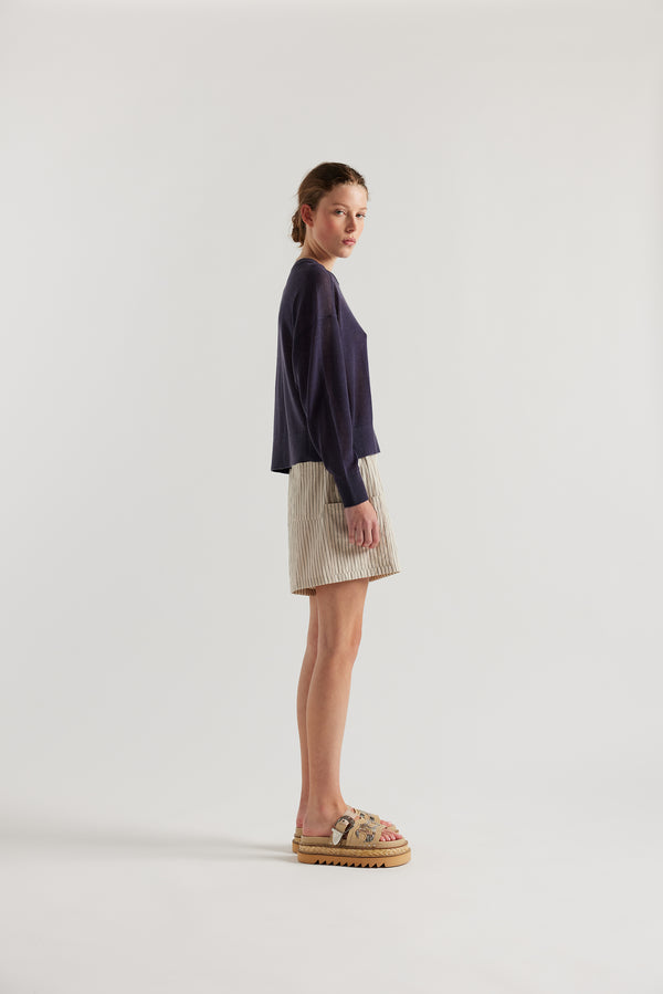 Side view of model in the ecru and black stripe vesper short, a wide loose fit short with elasticated waistband. 