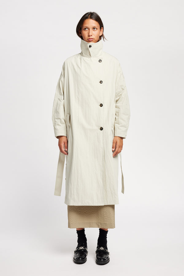 Front view of model wearing the Volt Trench in Bone collar up. A lightweight double-breasted trench coat with flap pockets