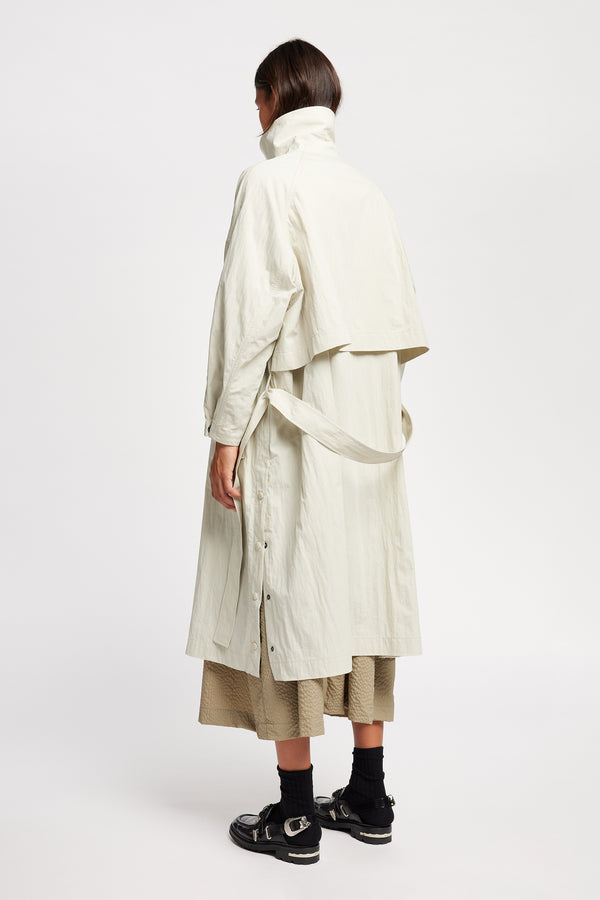 Back view of model wearing the Volt Trench in Bone collar up. A lightweight double-breasted trench coat with flap pockets