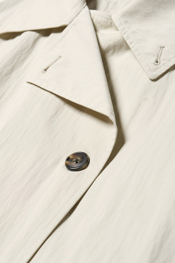 Close up collar detail shot of the Volt Trench in Bone. A lightweight double-breasted trench coat with flap pockets