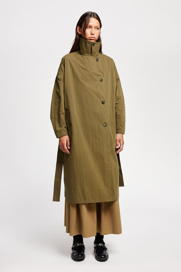 Front angle view of model wearing the Volt Trench in Kelp Green collar up. A lightweight double-breasted trench coat with flap pockets