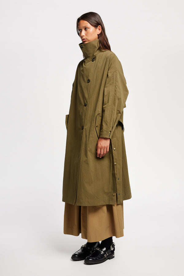 Front angle view of model wearing the Volt Trench in Kelp Green, collar up. A lightweight double-breasted trench coat with flap pockets