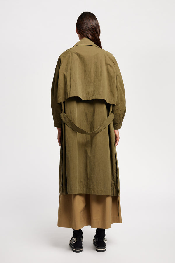 Back view of model wearing the Volt Trench in Kelp Green. A lightweight double-breasted trench coat with flap pockets