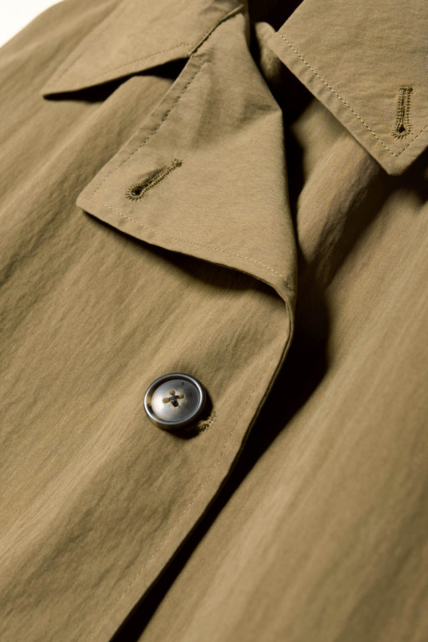 Close up collar detail shot of the Volt Trench in Kelp Green, collar up. A lightweight double-breasted trench coat with flap pockets