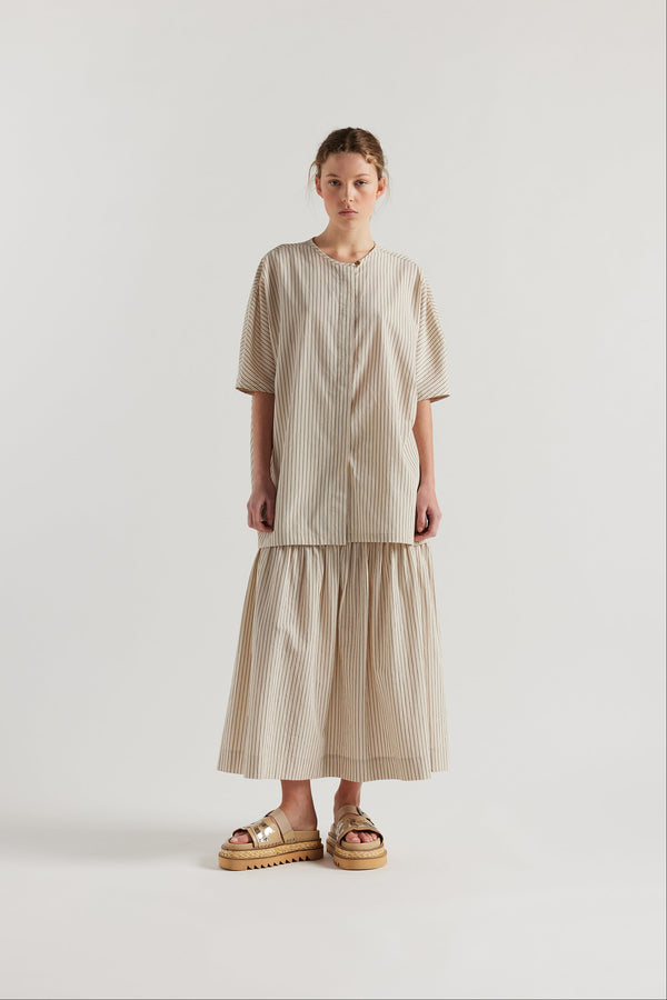 Front view of model in the oversized boxy yarn-dyed cotton top with round crew neck and concealed placket in Ecru with black pin stripe. 