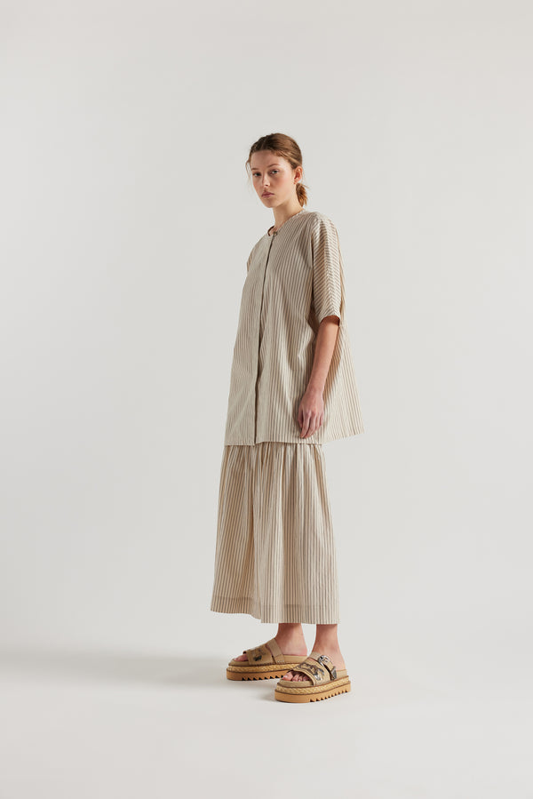 Front angle view of model in the oversized boxy yarn-dyed cotton top with round crew neck and concealed placket in Ecru with black pin stripe. 