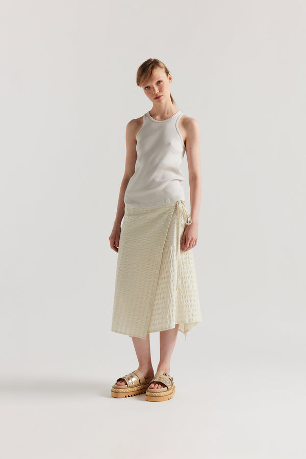 Front of Model wearing the Wing tank in Bone, off white. A slim-fit ribbed cotton tank with a slight racer neckline. A clean, minimal silhouette