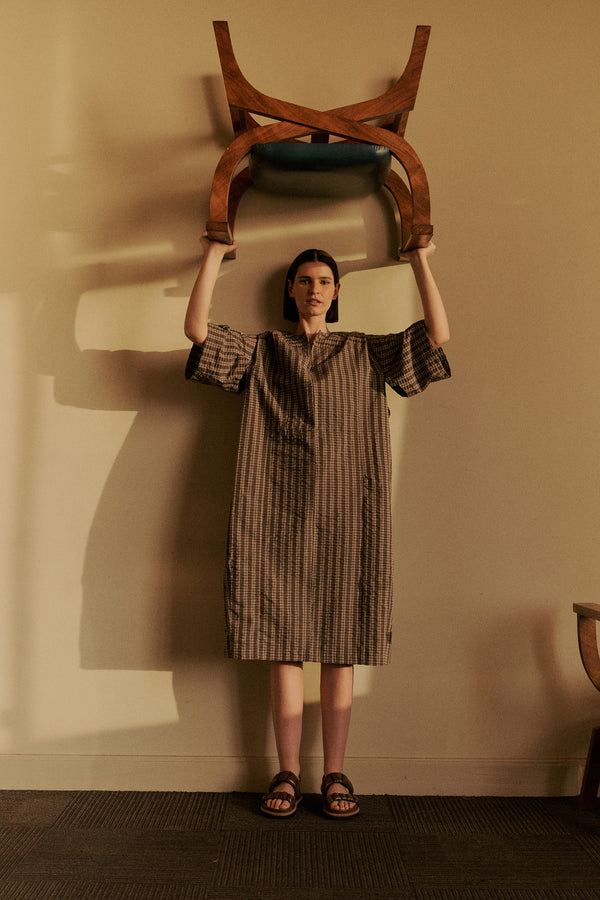 Front view of Woman wearing the Origin Dress in gingham seersucker brown check. A relaxed silhouette with internal tie, clean neckline, and subtle underarm split detail.