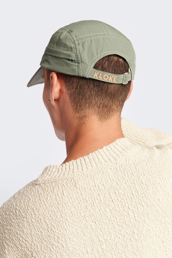 men - back of the Unisex olive green 5-panel zip cap in quick-dry technical nylon with a hidden zip pocket, adjustable back strap, and subtle embroidered Kloke branding