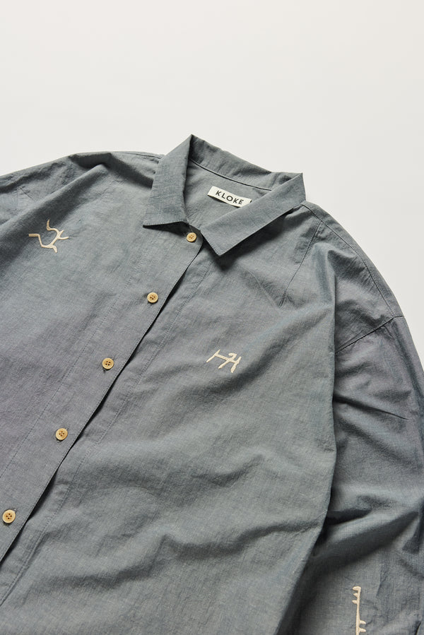 Detail of KLOKE embroidered shirt in blue grey, collar and shoulder darts, ecru embroidery and beige buttons