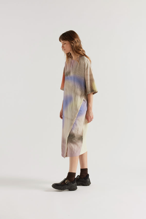 Three-quarter view of the Eon Dress in Aion Print showing double-layered asymmetric split front, fluid drape and mid-calf midi length