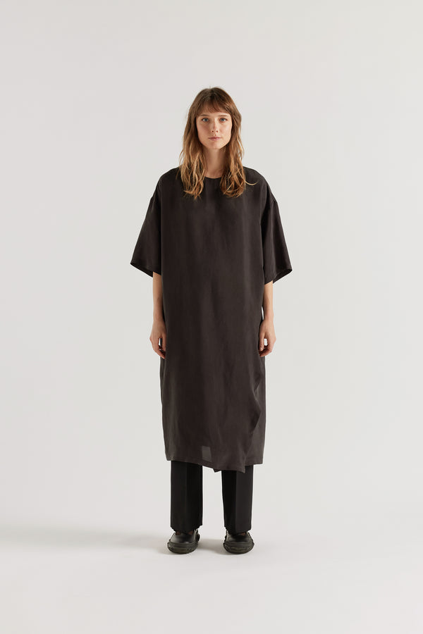 Front of Eon Dress in black layered over the Manta Pant showing daytime styling and fluid asymmetric midi silhouette.