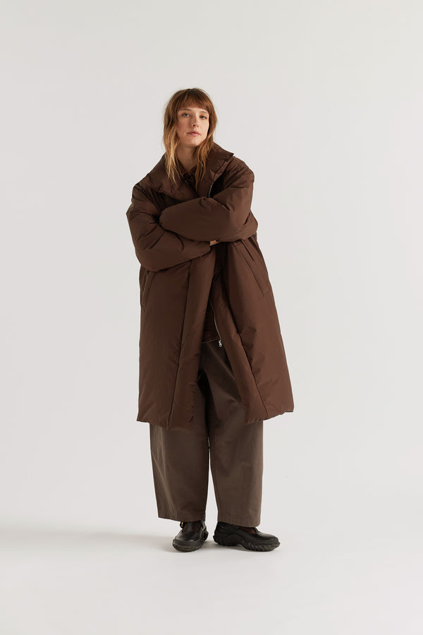 Front of model in Chocolate Brown Floating Puffa Coat worn open, showing full-length silhouette, down-filled high collar and centre-front zip with magnetic fastenings