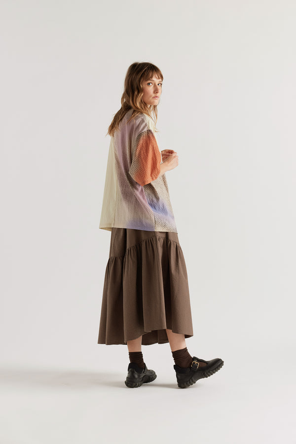 Back view of the Glimmer Top in Aion Print showing hip length, short-to-mid sleeves and fragmented asymmetric deity print in mauve, blue and orange