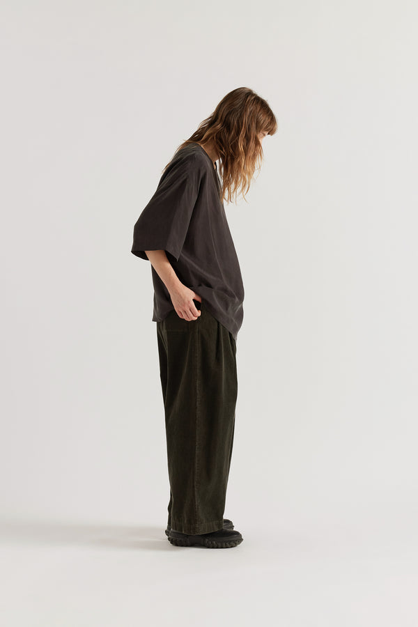 Side profile of the Glimmer Top in vintage black cupro, highlighting the asymmetrical front split and layered construction.