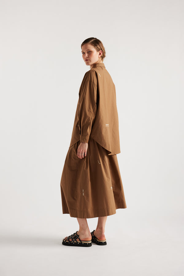 Model wears KLOKE embroidered skirt in walnut brown, back view