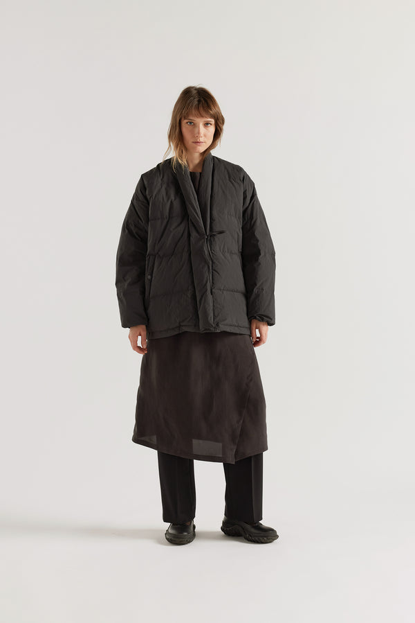 Front of model in Vintage black Nimbus Kimono Jacket worn closed with centre-front self-tie, showing quilted recycled down construction and wrap silhouette
