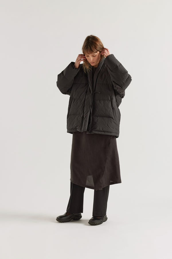 Front of model in Vintage black Nimbus Kimono Jacket worn closed with centre-front self-tie, showing quilted recycled down construction and wrap silhouette