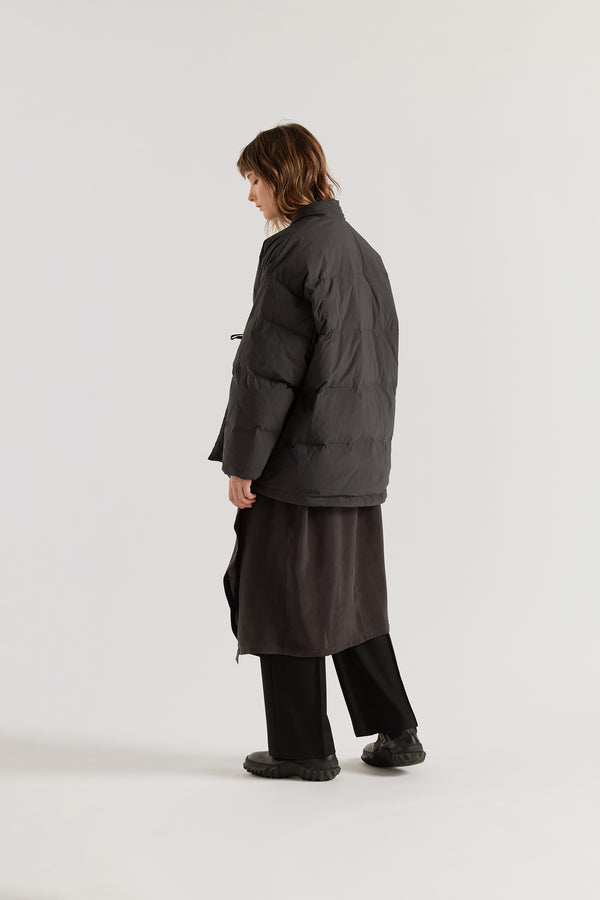 Back of model in Vintage black Nimbus Kimono Jacket worn closed with centre-front self-tie, showing quilted recycled down construction and wrap silhouette