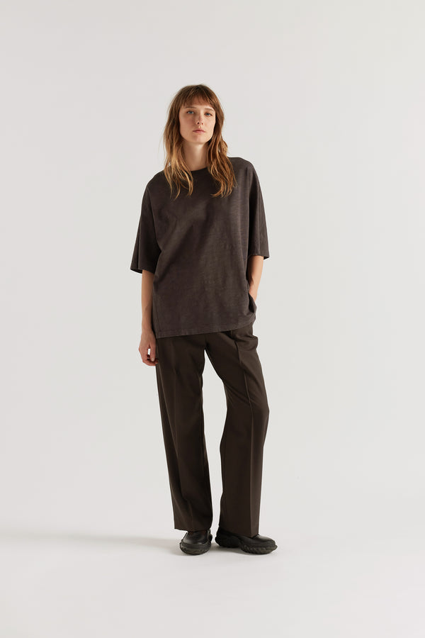 Front of female model in the black Overdyed Declare Tee in Nut Brown with a relaxed boxy fit and twisted sleeve detailing.