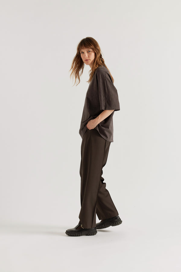 Side profile of model in the black Overdyed Declare Tee highlighting the loose sleeves and boxy fit.