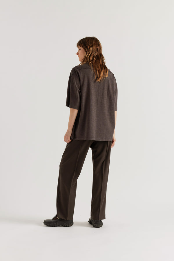 Back view of female model in the  black Overdyed Declare Tee in Nut Brown showing the relaxed silhouette.