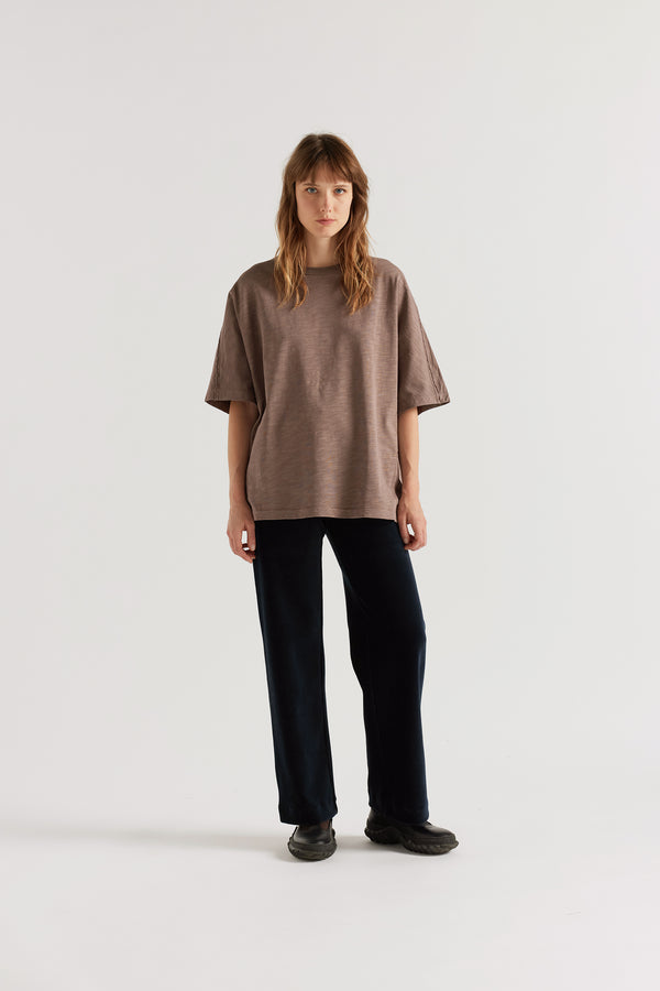 Front of female model in the brown Overdyed Declare Tee in Nut Brown with a relaxed boxy fit and twisted sleeve detailing.