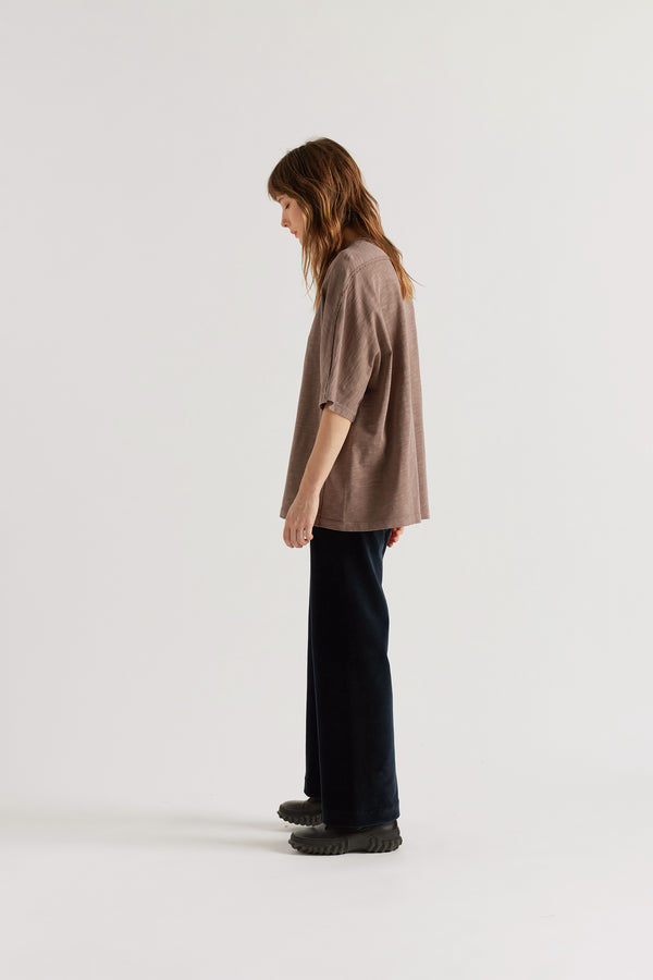 Side profile of model in the brown Overdyed Declare Tee highlighting the loose sleeves and boxy fit.