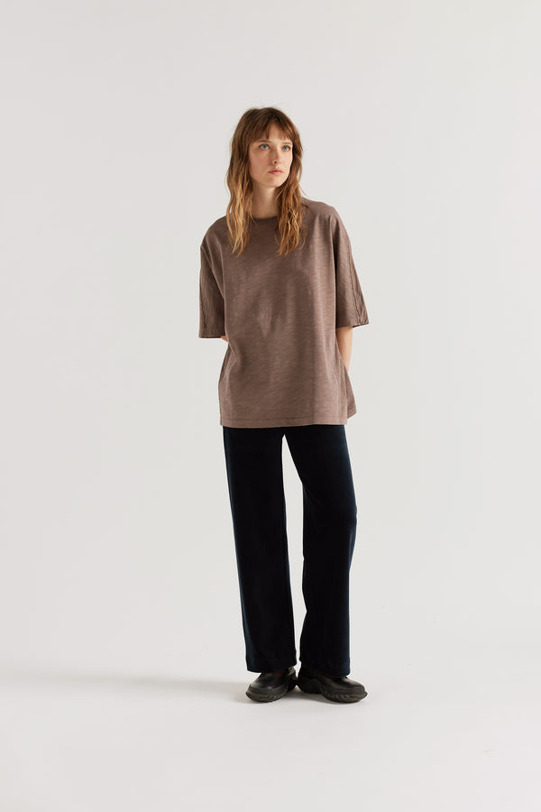 Front of female model in the brown Overdyed Declare Tee in Nut Brown with a relaxed boxy fit and twisted sleeve detailing.