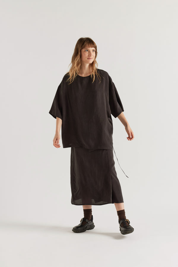 Front of the Purview Skirt in Vintage Black Cupro showing wrap A-line midi silhouette. 