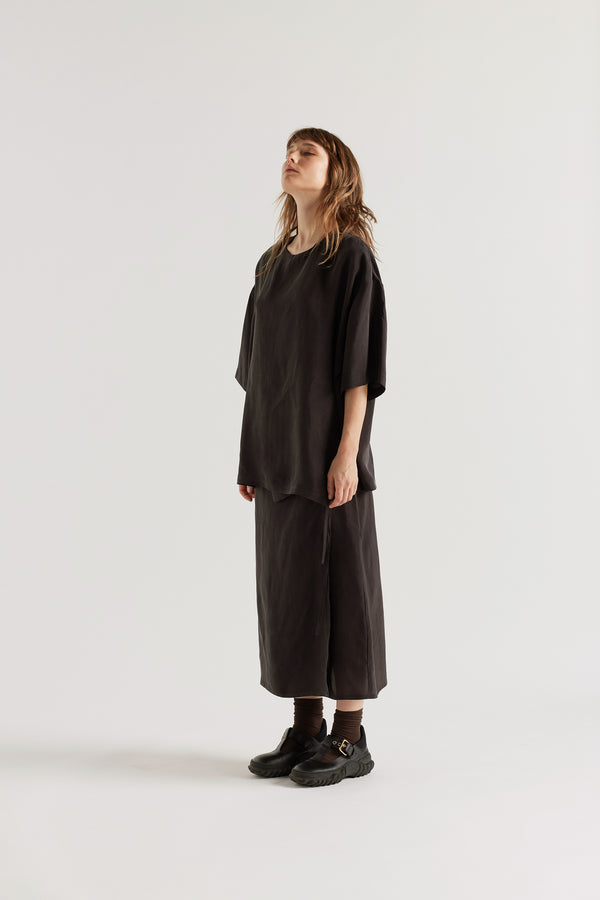 Front angle of the Purview Skirt in Vintage Black Cupro showing wrap A-line midi silhouette. 