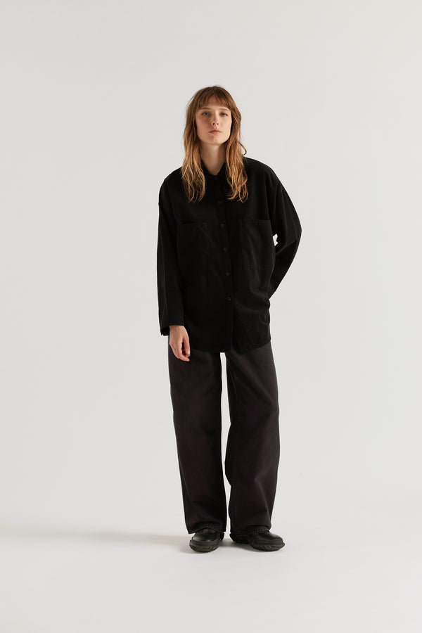 Refraction Cord Shirt in Black worn buttoned, showing edge-stitched stand collar, dropped sleeves, front patch pockets and double over-dyed cotton corduroy