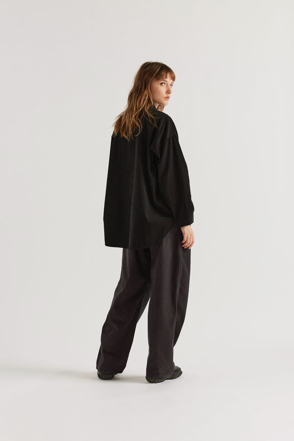 Back view of the Refraction Cord Shirt in Black showing dropped sleeve silhouette, rounded hemline and deep colour from garment double over-dye process