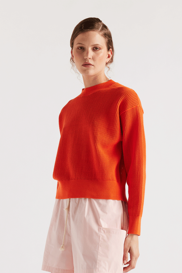 Model wearing KLOKE pointelle-knitted cotton sweater in dutch orange, front view
