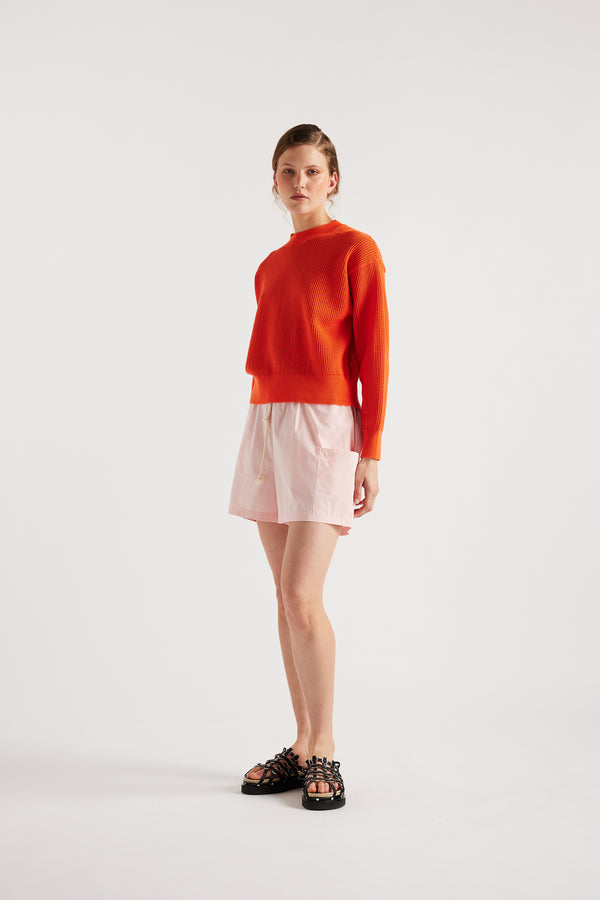 Model wearing KLOKE pointelle-knitted cotton sweater in dutch orange, front view