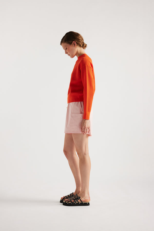 Model wearing KLOKE pointelle-knitted cotton sweater in dutch orange, side view