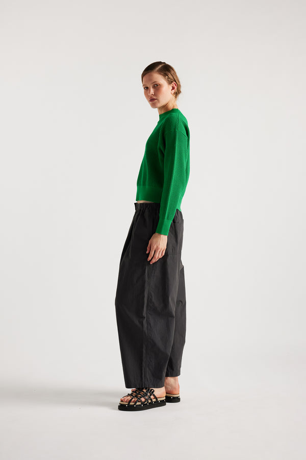 Model wearing KLOKE pointelle-knitted cotton sweater in vivid green, side view