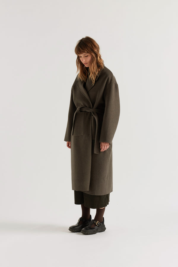 Retention Wool Coat in Olive Taupe worn closed, showing tailored single-breasted long silhouette, dropped shoulders and large front patch pockets