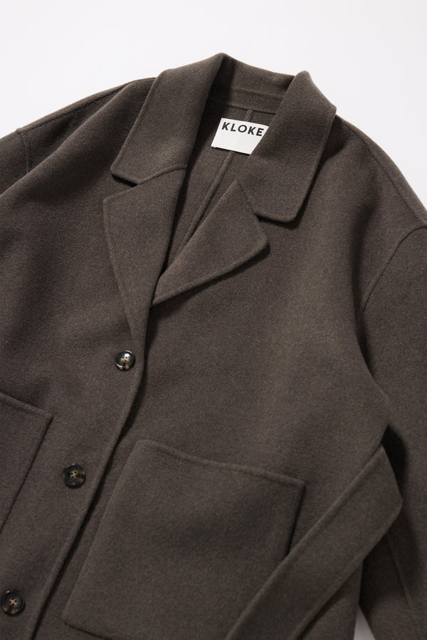 Close-up of hand-finished edge on the Retention Wool Coat in Olive Taupe, showing the clean seam-free finish of the double-faced wool cashmere construction