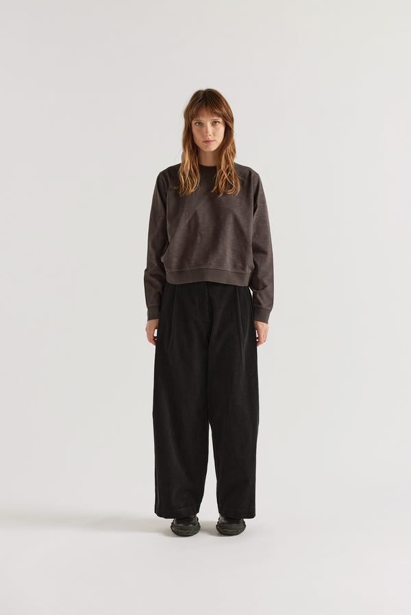 Black Willow Cord Pant front view showing pleat detail, wide balloon-shaped leg silhouette and double over-dyed corduroy in a semi-tailored women's trouser